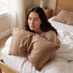 Frau am Morgen im Bett mit dem Seidenkissenbezug in Karamell, glatte Haut ohne Schlaffalten