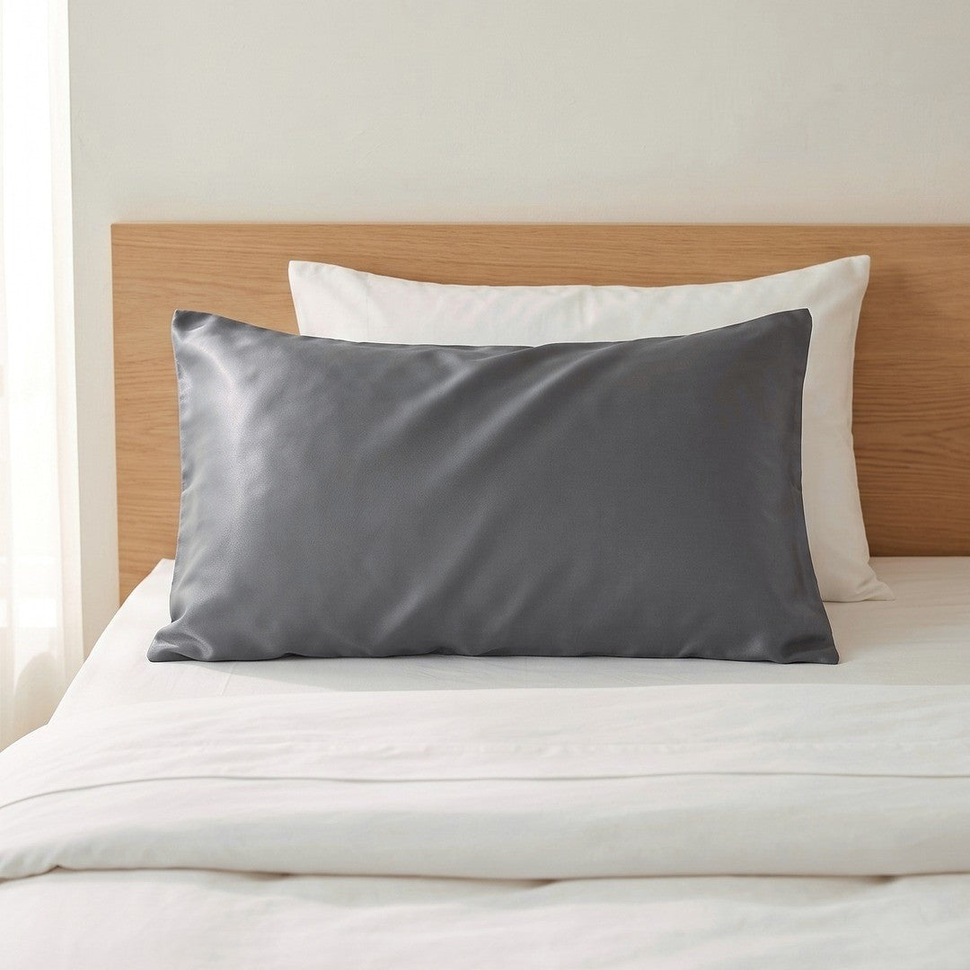 Seidenkissenbezug in Graphit auf einem gemachten Bett mit weißer Bettwäsche und Kopfteil aus Holz